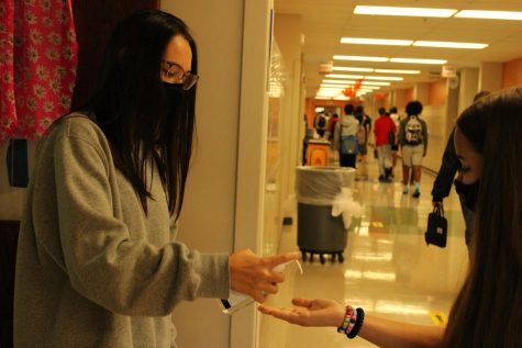 Freshman Allison Gosling squirts hand sanitizer into her classmates hand before they enter the classroom.